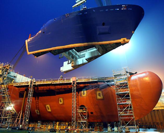 Im Trockendock der Warnemünder Werft von Aker Yards Germany wird die 420 Tonnen schwere obere Bugspitze an einen Containerschiffneubau vom Typ Aker CS 1700 gesetzt. Foto: Archiv/dpa