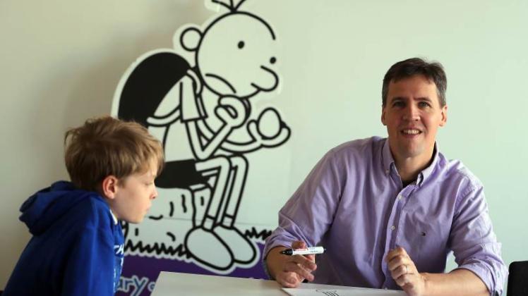Der US-amerikanische Kinderbuchautor Jeff Kinney (r.) zeichnet  und wird von Joshua beobachtet. Kinney ist mit seinen Büchern über den vorpubertären Greg mit einer Gesamtauflage von 115 Millionen der derzeit erfolgreichste Jugendbuchautor der Welt.   