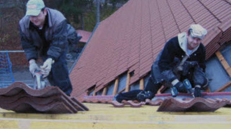 Sandro Möller und Ivo Hoffmann (r.) von der Dachdeckerei Petri aus Neuenkirchen brachten die letzten Pfannen auf das Dach des neuen Zwischengebäudes der Lübstorfer Schule.Werner Mett