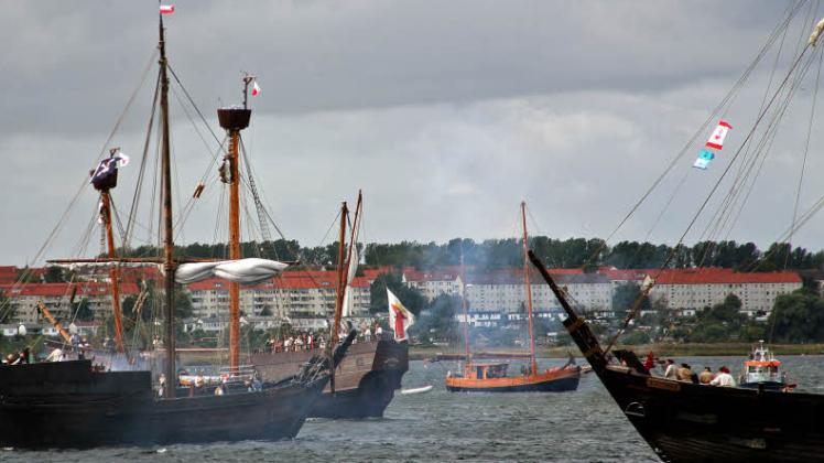 5. September 2009: vor dem Wismarer Hafen tobt eine Koggenschlacht. Die Kieler Kogge (links,  mit der Piratenflagge im Mast), wird von der „Lisa von Lübeck“ und der „Wissemara“ (rechts) unter Beschuss genommen.      
