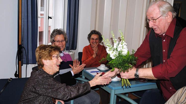 Behrend Böckmann (l.) beglückwünschte Elfriede Lammek zu 25 Jahren Mitgliedschaft bei den Güstrower Plattsnackern mit einem Blumenstrauß.