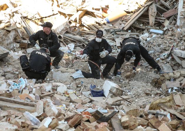 Polizisten durchsuchen die Trümmer des Mehrfamilienhauses. Polizisten durchsuchen die Trümmer des Mehrfamilienhauses.