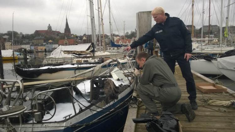 Ein Kriminaltechniker der Flensburger Kripo sichert zusammen mit Sven Kurz von der Bundespolizei  (re.) Spuren auf einem der ausgebrannten Boote. 