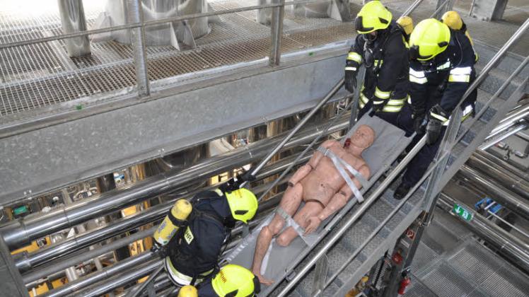 Eine Schweiß treibende Angelegenheit: Über eine Treppe müssen die vier Feuerwehrmänner mit Atemschutzgeräten die geborgene Person in Sicherheit bringen. Fotos: rüdiger rump Eine Schweiß treibende Angelegenheit: Über eine Treppe müssen die vier Feuerwehrmänner mit Atemschutzgeräten die geborgene Person in Sicherheit bringen. Fotos: rüdiger rump