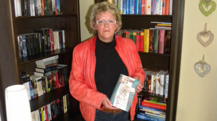 Petra Schulz vor der hauseigenen Bibliothek. Zu ihren Lieblingsbüchern gehören die Romane von Iny Lorentz, wie hier „Flammen des Himmels“.  