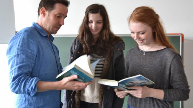 Autor David Fermer las gemeinsam mit Carina Hingst (Mitte) und Svea Losigkeit aus dem zweisprachigen Buch „Surf4ever“.  