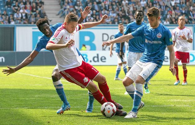 Die Rostocker Alexandre Mendy (l) und Sascha Schünemann (r) kämpfen mit dem Leipziger Daniel Frahn (M) um den Ball. RB Leipzig gewinnt am Ende mit 1:0. 