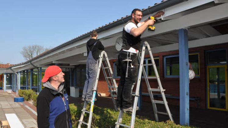 Zimmerergeselle Marco Holm (re.) und Praktikant Lucas Wolf montieren  weiße Hartfaserplatten an der Blende der Dachüberstände. Links: Schwimmmeister Lutz Stüven. 
