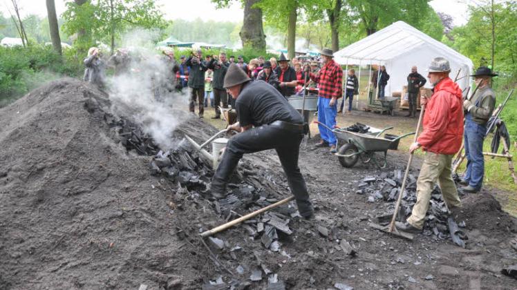Schicht für Schicht wird die Holzkohle  am geöffnete Meiler abgelöscht:  Hartmut Thienen vom Harzer Köhlerverein  und Freunde aus Bahlenhüschen bei der Ernte.   Fotos: Werner Mett 