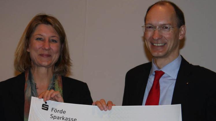 Caje Petersen von der Förde Sparkasse überreicht Beate Kennedy von der Wilhelm-Lehmann-Gesellschaft einen Scheck in Höhe von 4500 Euiro. 