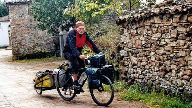 Jens Kinders ganzer Reisebesitz ist auf Rad und Anhänger verteilt. Bekleidet mit seiner geliebten Cordhose und der roten Strickmütze ist er in Galizien unterwegs.  Foto: Fotos privat