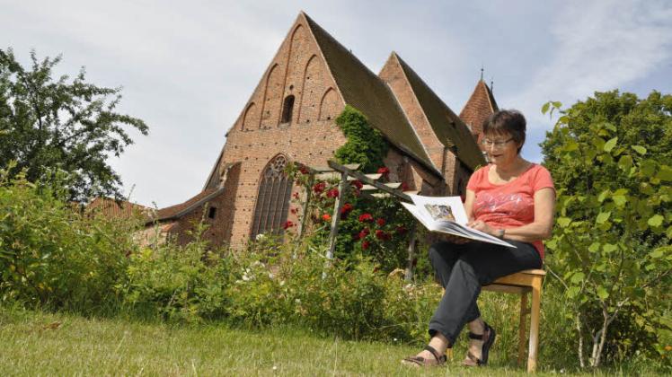 Mitorganisatorin Eva Doßmann blättert im Rehnaer Klostergarten in den Märchen von Heinrich Seidel. 