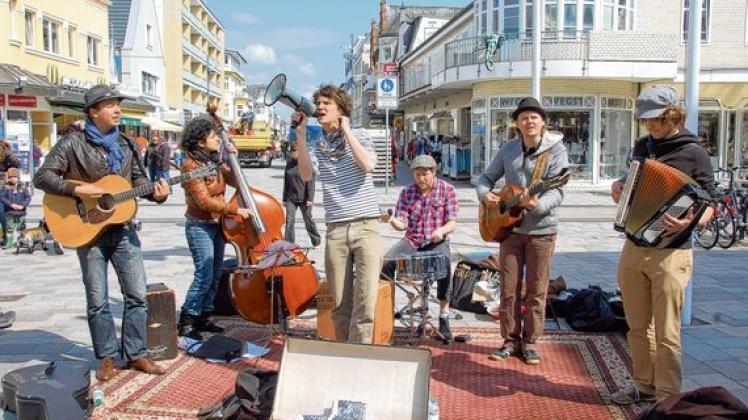 Straßenmusiker Felix Meyer (M.) tritt mit seiner Band zurzeit  in der Westerländer Fußgängerzone auf.  Foto: Brudnitzki