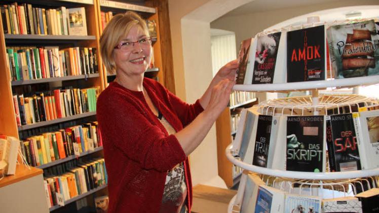 Bibliothekarin Brigitte Steinberg steht an einem Rollregal mit Krimiromanen. Viele Leser leihen diese gerne aus. 