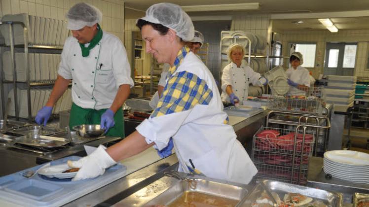 Erst kochen, dann verteilen - in der Großküche stehen auch die Köche, wie hier Ulrike Fritsche, am Verteilerband. Koch Stefan Blümke (li.) ist heute für die Meerrettichsoße zuständig. 