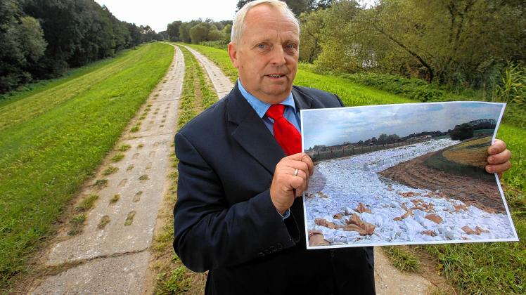 Landwirtschaftsminister  Till Backhaus zeigt bei Neu Kaliß während der Abnahme der Deicherweiterungen zum Schutz bei künftigem Elbe-Hochwasser ein Foto von Sandsackmauern bei der Überflutung im Jahr 2013.  