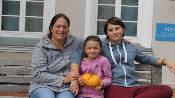 Die kleine Tomatenexpertin Melanie Klug (7) aus Groß Görnow präsentiert ganz stolz mit ihrer großen Schwester Elisa (14) sowie ihrer Mama Stefanie die Rekordtomate. 