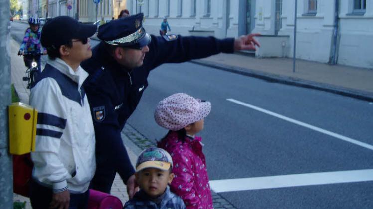 Ralf-Theo Mundt erklärt einem Kind, das vom Papa   in die Schule gebracht wird, wie man sicher über die Straße kommt. Fotos: münchow 