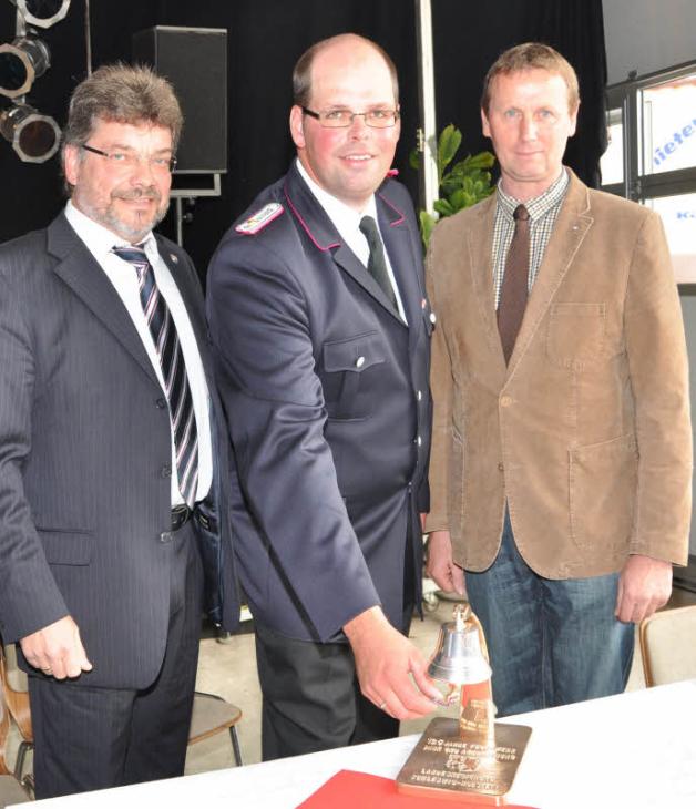 Freuten sich über ein Geschenk der Landesregierung, eine Messing-Tischglocke (von links):  Kreispräsident Peter Labendowicz, Wehrführer Jörg Göttsche und Bürgermeister Volker Bolten.