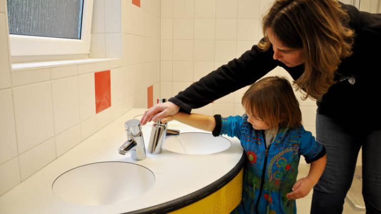 Funktionstest: Die dreijährige Milla durfte gestern schon mal den neuen Waschraum testen. Ein Druck und schon fließt das Wasser. Kita leiterin Heike Facklam zeigt, wie es geht.  Fotos: Ralf Badenschier (3) 