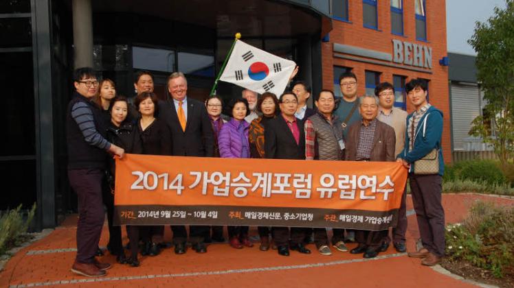 Gruppenfoto mit Waldemar Behn: Ein Banner ihrer Studienreise zeigt den Koreanern an, um welche Reisegruppe es sich handelt – auch vor dem Eingang der Firma Behn im Kadekerweg. 