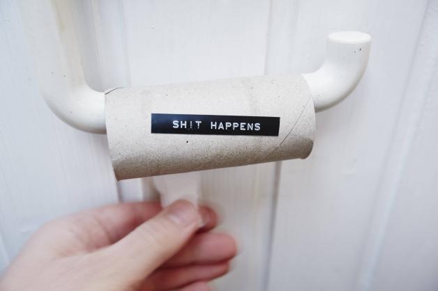 Hand reaching for an empty toilet paper roll with message shit happens model released PUBLICATIONxIN