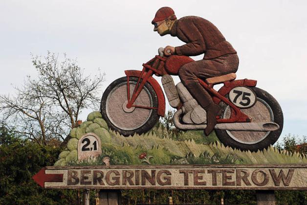 Den Motorradfahrer, der den Weg zur berühmten Teterower Grasbahn weist, schuf Jim Schütz.