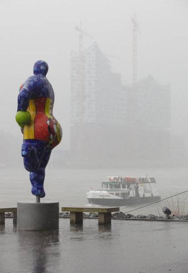 Neblige Aussichten: Eine Plastik von Niki de Saint Phalle steht am 30.01.2013 am Hamburger Hafen vor der Kulisse der Baustelle der Elbphilharmonie. Foto: dpa