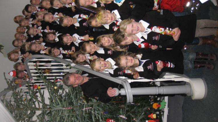 Stolze Kinder der evangelischen Kindertagesstätte vor ihrem geschmückten Weihnachtsbaum mit Jörn Groth.  