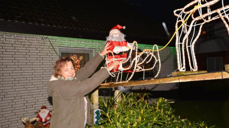 Christine Brandenburg rückt den Weihnachtsmann auf seinem beleuchteten Schlitten zurecht. Fotos: REgina Mai 