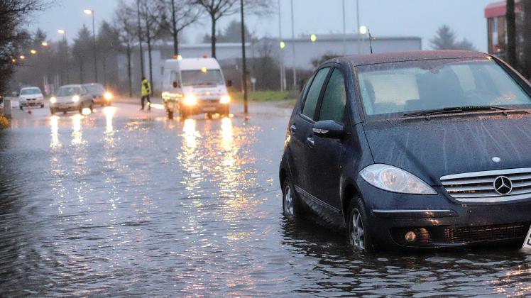 Die Lise-Meitner-Straße in Flensburg ist an Heiligabend überschwemmt. Der ein oder andere fährt trotzdem weiter.