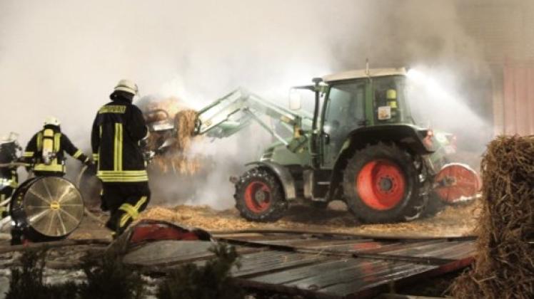 Mit Hilfe eines Traktors wurden die Rundballen aus dem brennenden Stall geholt.  Foto: Michael Kuhr