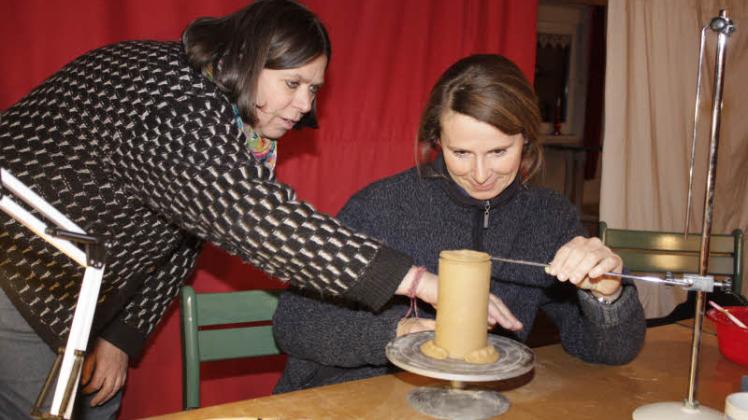Susanne Kramer (l.) zeigt Kati Hoeft, wie man mithilfe des Tonabschneiders den Becher gerade abschneidet. 