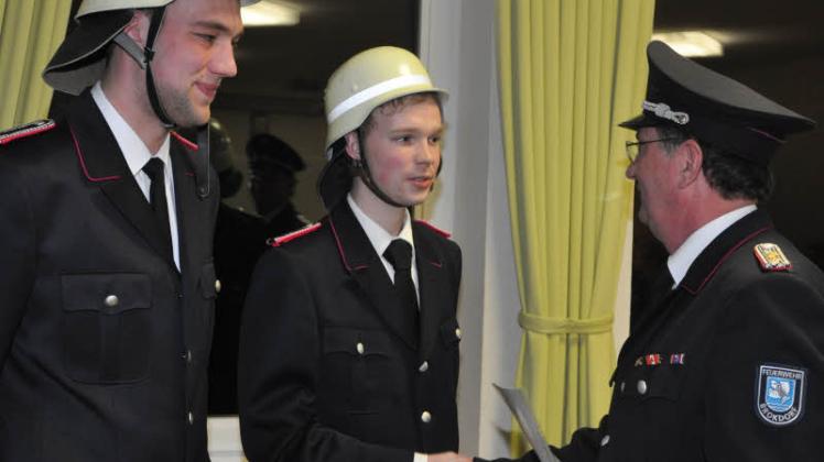 Wehrführer Thorsten Block verpflichtet Marten Looft (links) und Max Gitschel zu neuen Feuerwehrmännern. 