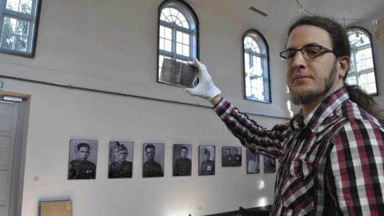 Thomas Kühn vom Museum hält eine Negativ-Platte, die von Elli Hartmann aufgenommen wurde, in Händen. An den Wänden hängen bereits die Soldatenfotos.  Fotos: Hirschmann/Museum 