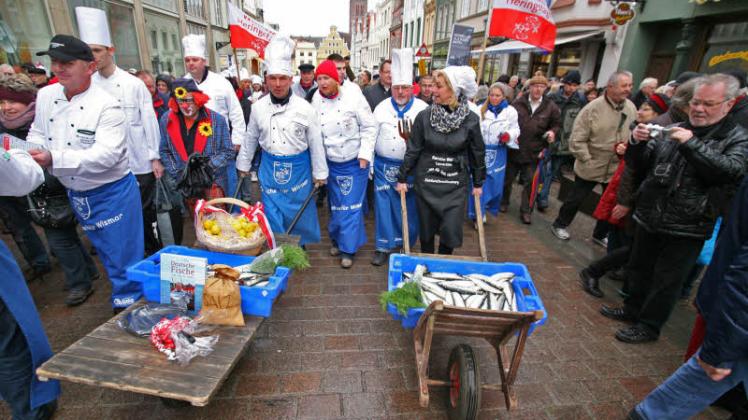 Der Zug der Köche, begleitet von hunderten Besuchern, bahnt sich den Weg durch Wismars Altstadt. Die frische Ware wurden von der Kommunalprominenz, Bürgermeister Thomas Beyer und Landrätin Kerstin Weiss, persönlich über das Pflaster gekarrt.