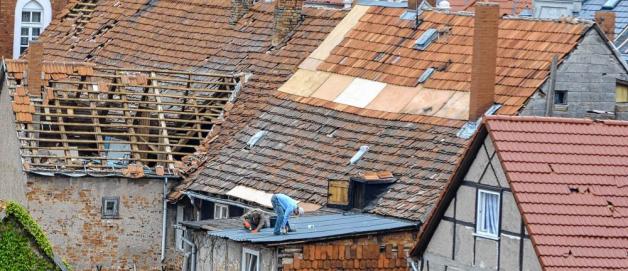 In schwindelerregender Höhe schließen die Handwerker kleinere Löcher in den Dächern der Häuser in der Bützower Innenstadt.