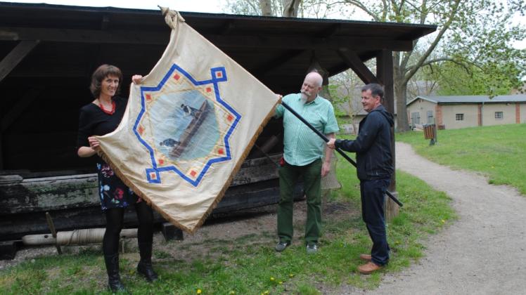 Reich verziert und gut erhalten: Die Fahne der Schweriner Fischzunft brachte Hans-Jürgen Diercke (M.) ins Volkskundemuseum. Gesine Kröhnert und Volker Janke freuen sich sehr darüber. 
