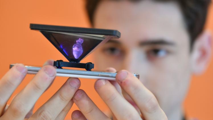 Aliaksandr Piarerva hält im Rahmen seines Beitrags "Dreidimensionales Lernen" ein Handy mit einem aufgesetzten Hologramm in den Händen.