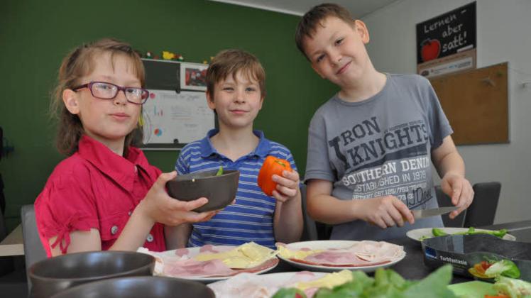 Bereiten das Frühstück vor: Jossy Lana, Anthony Joel und Maurice (v. l.) aus der vierten Klasse schneiden Obst und Gemüse zurecht und richten Wurst und Käse an.  