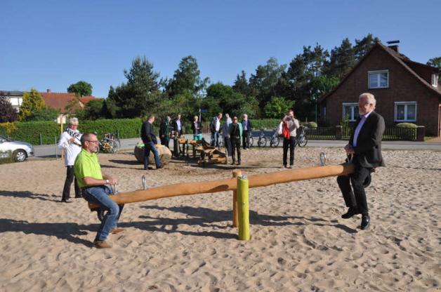 Gemeindevertreter Peter Tiedemann (l.) und Landrat Rolf Christiansen probieren die Wippe auf dem neuen Spielplatz aus.
