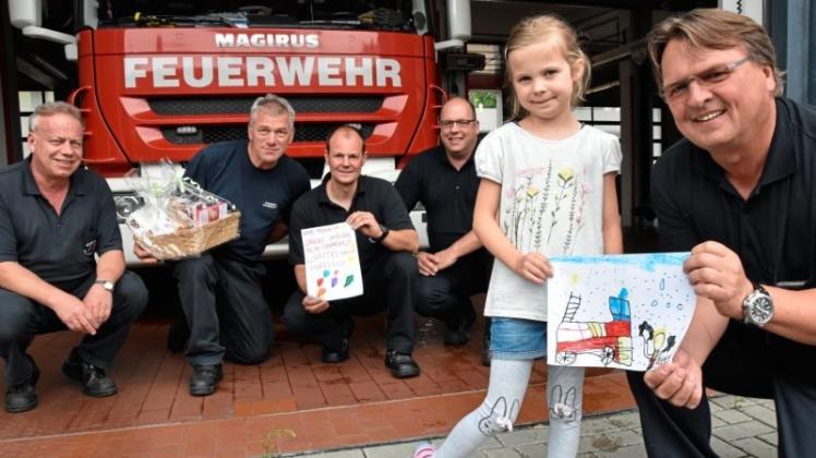 Lilly übergibt ein gemaltes Bild vom Einsatz an Feuerwehrchef Thomas Stalinski (rechts). Darüber freuen sich auch die Kollegen (von links) Thomas Grotelüschen, Michael Hübner, Marcel Bruhnke und Sven Willms.
