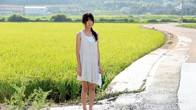 Dohee (Kim Sae-ron) steht in einem schmutzigen weißen Kleid zwischen den Feldern. Das misshandelte Mädchen vergisst ihr Zuhause, wenn sie alleine am Strand tanzt. 
