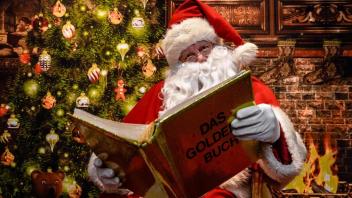 Ein Weihnachtsmann liest aus einem Goldenen Buch.