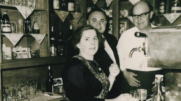 In ihrem Element: Ein Bild aus den frühen 1960er Jahren zeigt Agnes Schröder und ihren 1998 verstorbenen Mann Fritz (rechts) gemeinsam mit einem Gast hinter der Theke der Kunkemühle in Moorlage. 