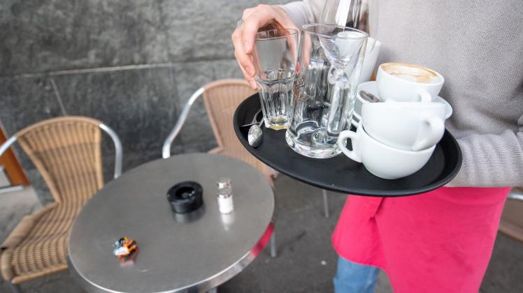 Eine Servicekraft räumt die Tische in einem Café ab
