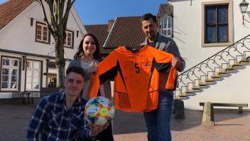 Sebastian Dude (links) mit dem Fifa-Spielball und dem Trikot, die er für die Ukraine versteigert. Seine Freunde unterstützen ihn dabei.