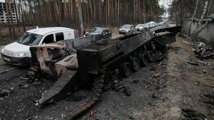 Autos fahren an einem zerstörten russischen Panzer vorbei, während ein Fahrzeugkonvoi zur Evakuierung von Zivilisten Irpin am Stadtrand von Kiew (Ukraine) verlässt.
