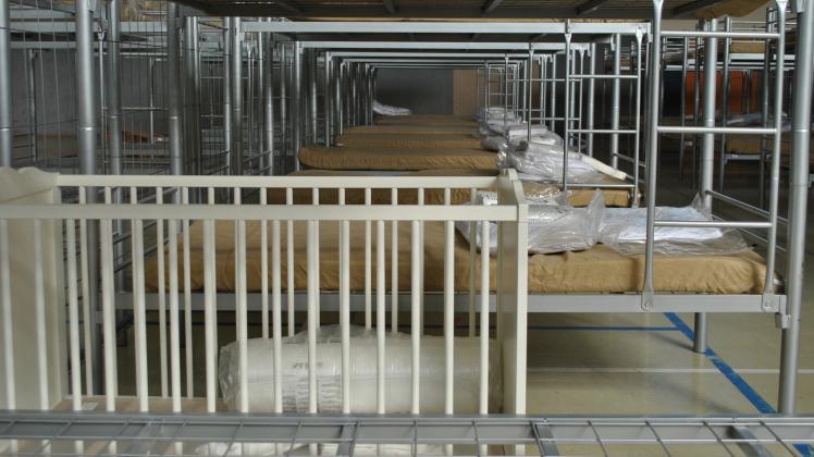 Ein Kinderbett zwischen den Etagenbetten in der Halle am Stubbenweg. Hier werden Menschen jetzt aus der Ukraine untergebracht.