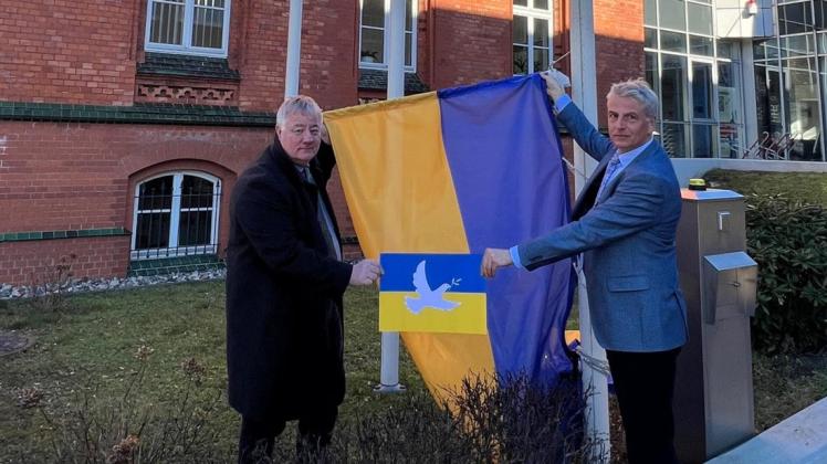 Der Präsident der Handwerkskammer Ostmecklenburg-Vorpommern (HWK) Axel Hochschild (l.) und Hauptgeschäftsführer Jens-Uwe Hopf hissen die ukrainische Staatsflagge.
